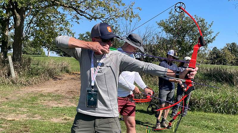 Employees aiming bows during an outdoor archery activity