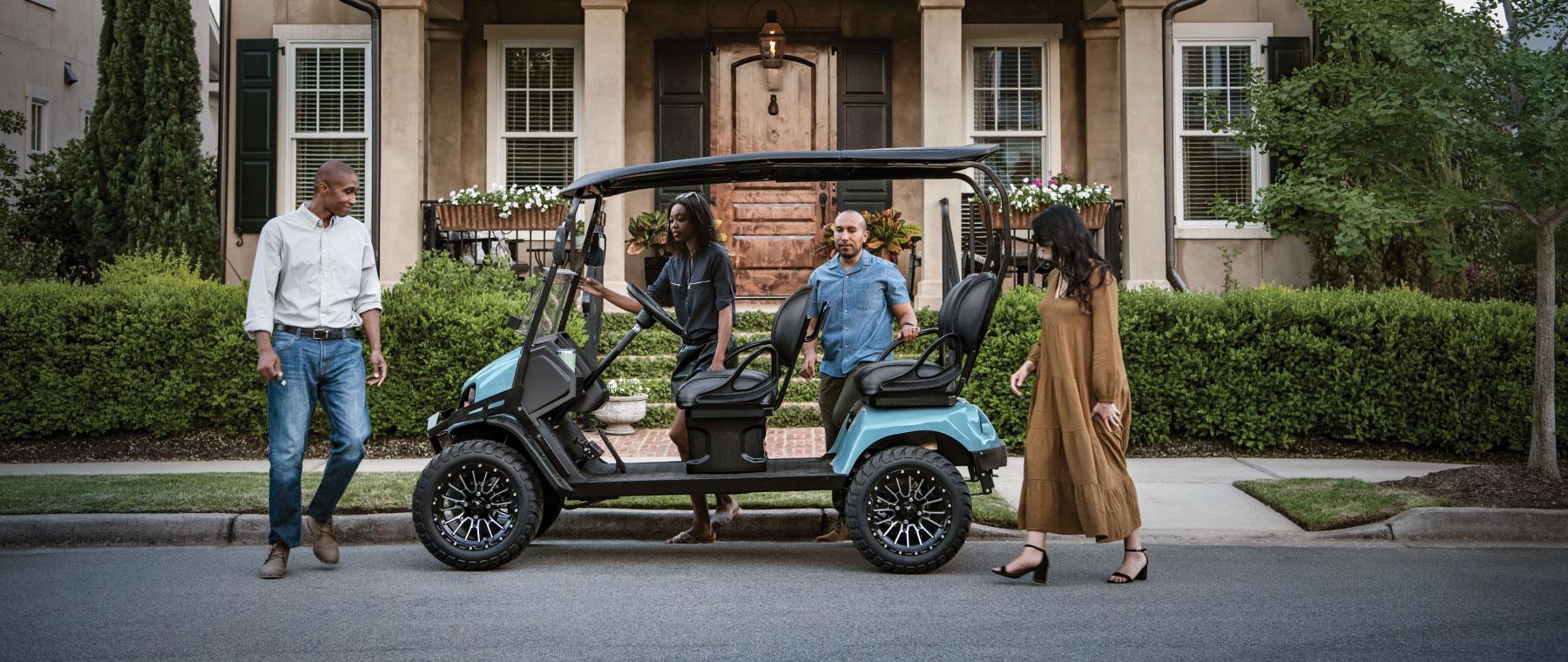 couples infront of house getting on golf cart